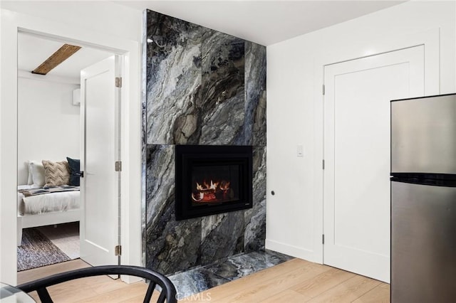 details featuring stainless steel refrigerator, wood-type flooring, and a tile fireplace