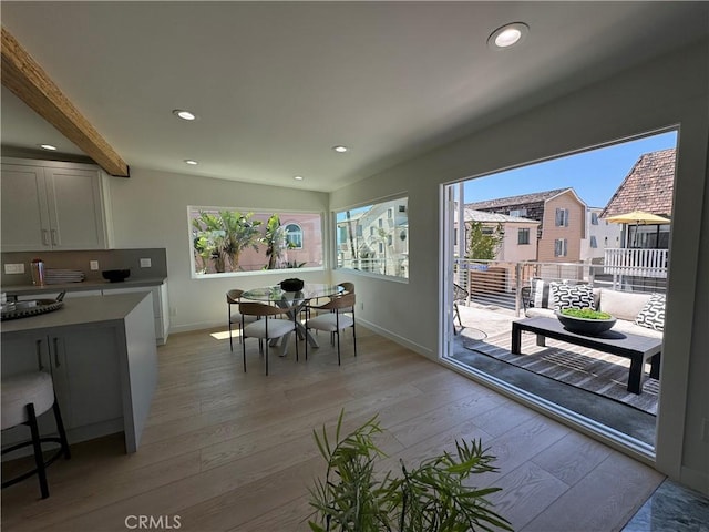 dining space featuring beam ceiling and light hardwood / wood-style flooring