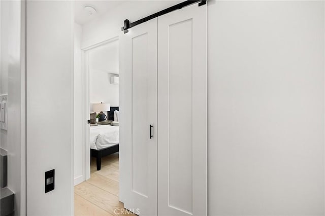 corridor featuring a barn door and light hardwood / wood-style flooring