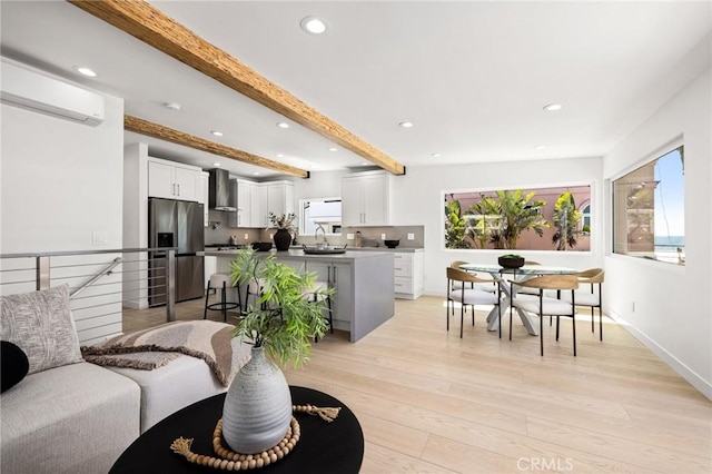 living room featuring sink, beam ceiling, and light wood-type flooring