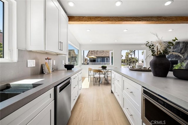 kitchen with light hardwood / wood-style flooring, white cabinetry, beam ceiling, tasteful backsplash, and stainless steel dishwasher