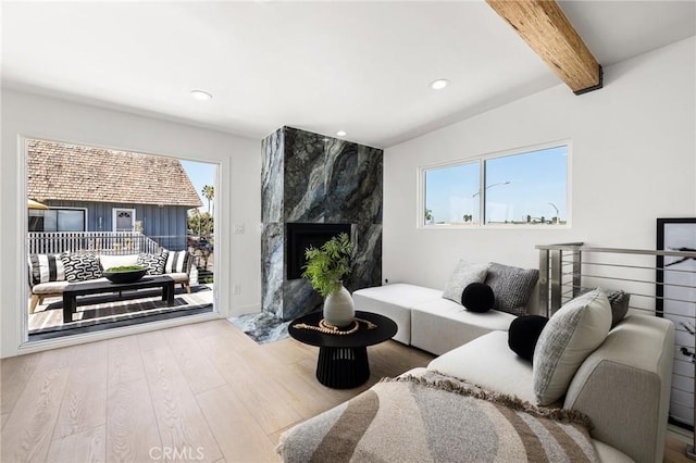 living room featuring beamed ceiling, hardwood / wood-style floors, and a high end fireplace