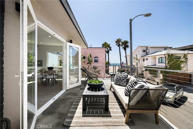 balcony featuring a water view and an outdoor living space