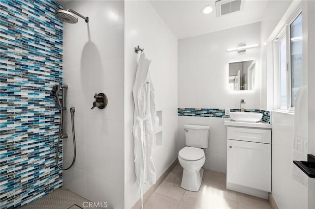 bathroom featuring tile patterned floors, toilet, tile walls, a tile shower, and vanity