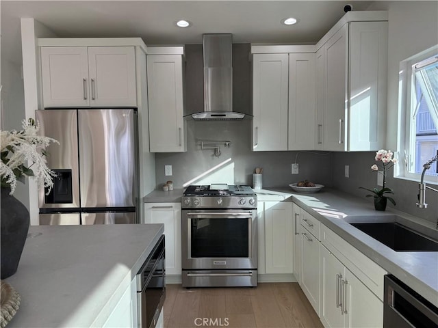 kitchen with white cabinetry, appliances with stainless steel finishes, and wall chimney range hood