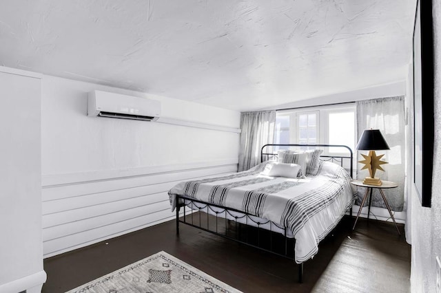 bedroom with a wall mounted air conditioner, vaulted ceiling, and dark wood-type flooring