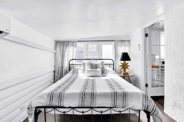 bedroom featuring a wall mounted air conditioner, vaulted ceiling, and hardwood / wood-style flooring