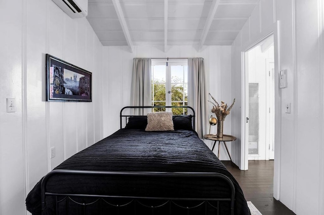 bedroom with a wall unit AC, beamed ceiling, and dark wood-type flooring