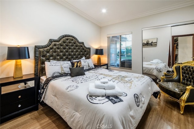 bedroom with a closet, hardwood / wood-style floors, and crown molding