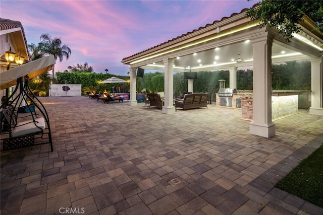 patio terrace at dusk with exterior kitchen, grilling area, and a gazebo