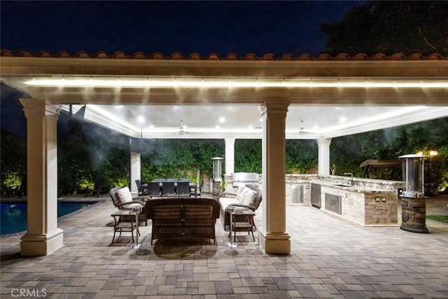 patio at twilight with exterior kitchen, ceiling fan, a gazebo, and sink