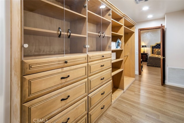 walk in closet with light hardwood / wood-style floors