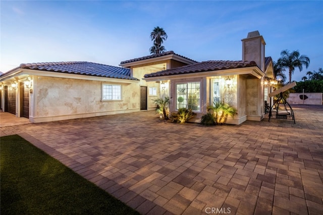 back house at dusk featuring a patio area