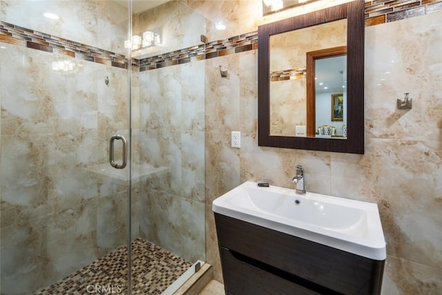 bathroom with tile walls, a shower with door, and vanity