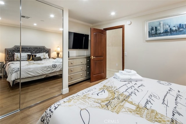 bedroom with hardwood / wood-style flooring, a closet, and crown molding