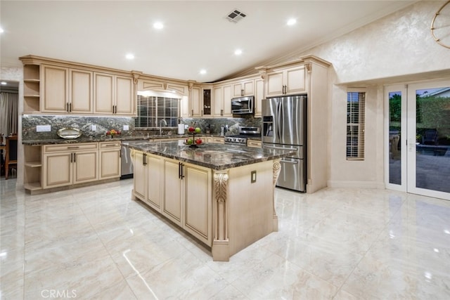 kitchen with appliances with stainless steel finishes, crown molding, dark stone counters, and a kitchen island