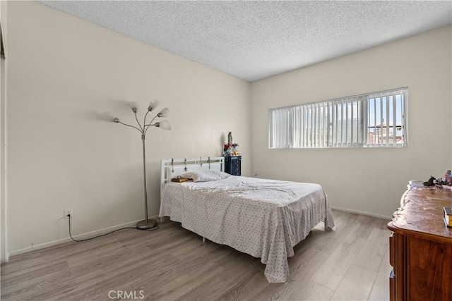 bedroom with light hardwood / wood-style floors and a textured ceiling