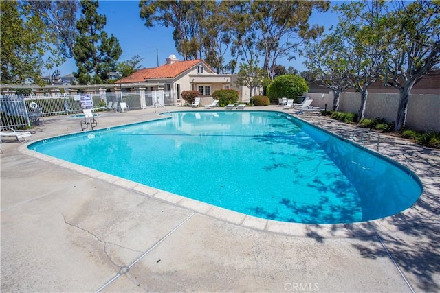 community pool featuring fence and a patio area