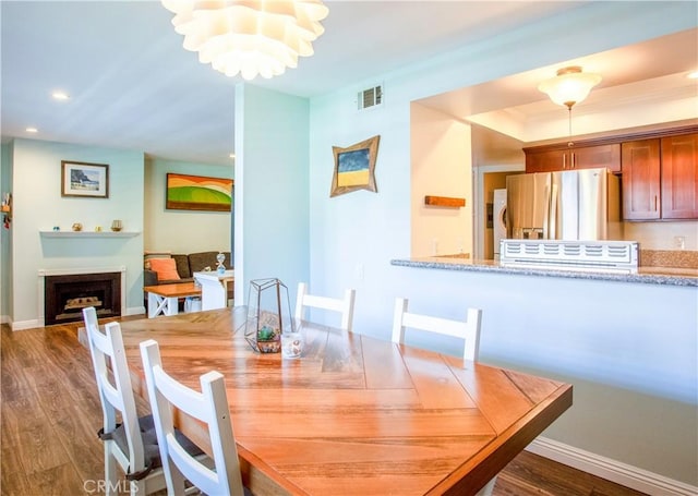 dining room with wood finished floors, recessed lighting, baseboards, a chandelier, and a tray ceiling