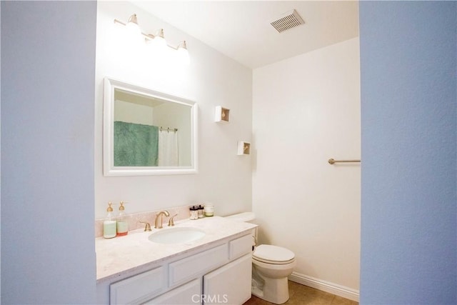 bathroom with toilet, vanity, and tile patterned floors
