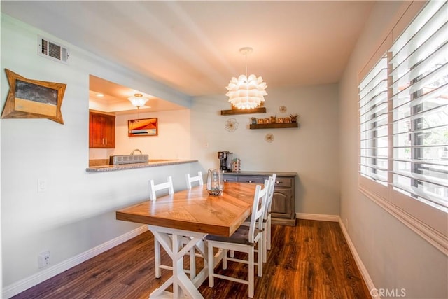 dining area featuring dark wood-type flooring, baseboards, and a chandelier