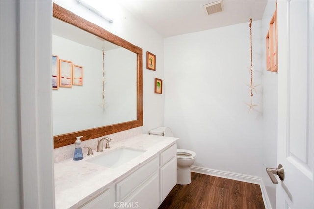 bathroom featuring toilet, vanity, wood finished floors, and baseboards