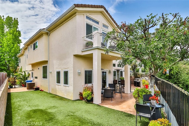 back of property with a balcony, a patio, central AC, and a yard