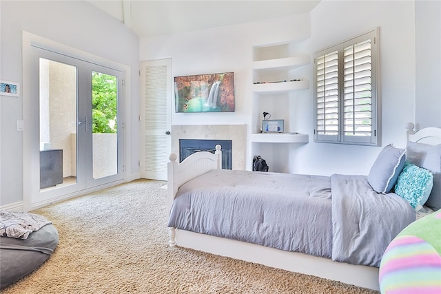 carpeted bedroom featuring multiple windows, access to outside, and a premium fireplace