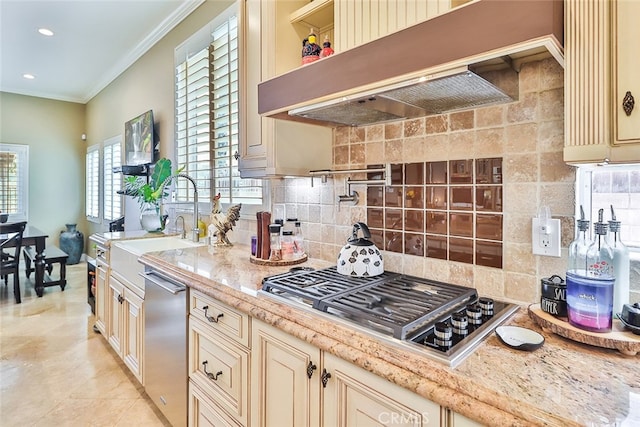 kitchen with appliances with stainless steel finishes, tasteful backsplash, crown molding, cream cabinets, and extractor fan