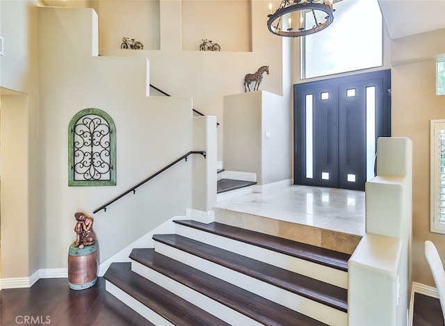 foyer entrance with a notable chandelier, dark wood-type flooring, and a high ceiling