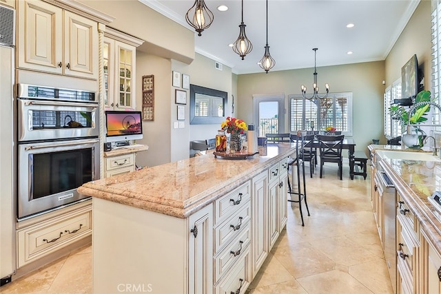 kitchen with appliances with stainless steel finishes, hanging light fixtures, crown molding, a center island, and cream cabinets