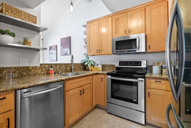 kitchen with dark stone counters, stainless steel appliances, sink, and lofted ceiling