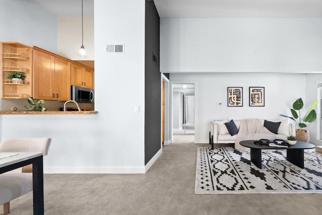 carpeted living room with a high ceiling and sink