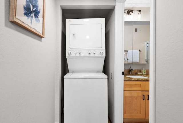 laundry area featuring stacked washer / dryer and sink