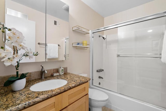 full bathroom featuring enclosed tub / shower combo, vanity, and toilet