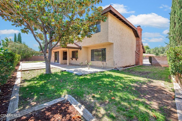 rear view of house with a lawn and a patio