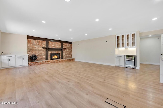 unfurnished living room featuring light wood-type flooring, a fireplace, and beverage cooler