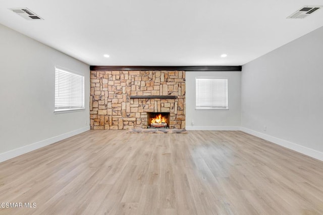 unfurnished living room with a fireplace, light hardwood / wood-style floors, and a healthy amount of sunlight