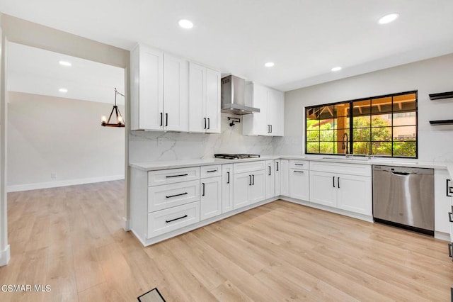 kitchen with dishwasher, wall chimney exhaust hood, sink, light hardwood / wood-style floors, and white cabinets