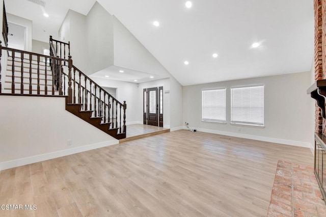 unfurnished living room with high vaulted ceiling and light wood-type flooring