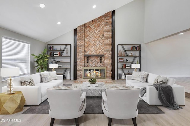 living room with a fireplace, high vaulted ceiling, and light hardwood / wood-style floors