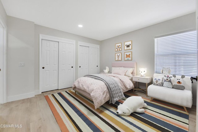 bedroom with light wood-type flooring and two closets