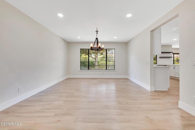 unfurnished dining area with a chandelier and light wood-type flooring