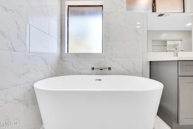 bathroom with a bathing tub, vanity, and tile walls