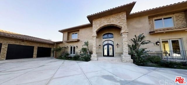 mediterranean / spanish-style house with a garage and french doors