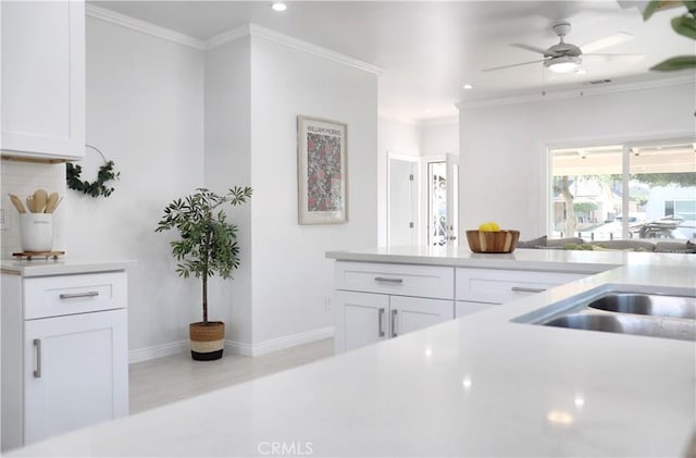 kitchen with white cabinetry, ceiling fan, light hardwood / wood-style flooring, backsplash, and crown molding