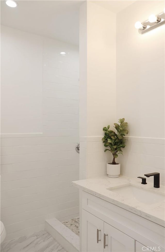 bathroom with vanity, tile walls, and tiled shower