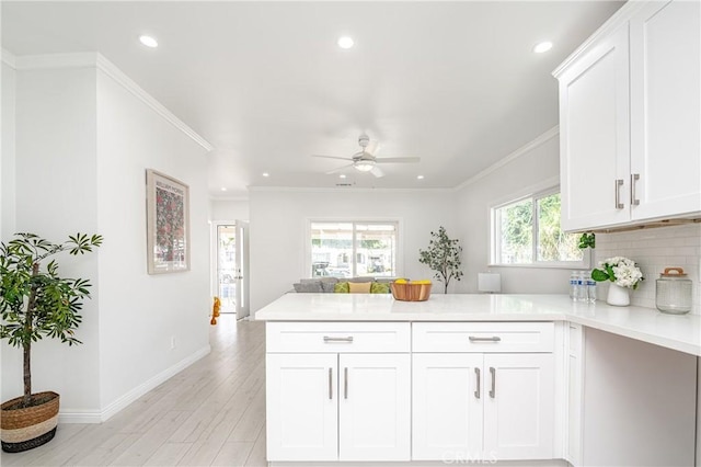 kitchen featuring white cabinets, light hardwood / wood-style flooring, a healthy amount of sunlight, and crown molding