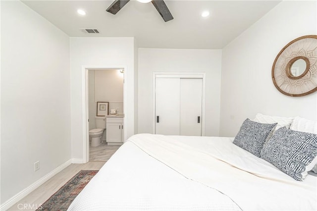 bedroom with ceiling fan, light hardwood / wood-style floors, ensuite bath, and a closet