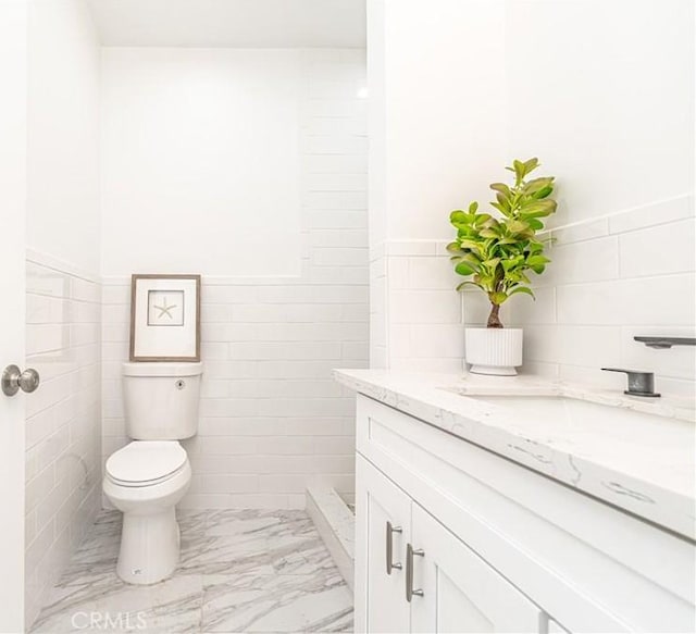 bathroom featuring vanity, tile walls, and toilet